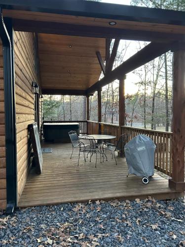 a wooden deck with a table and chairs on it at The Knotty Pine Cabin at Cabins of Wolf Pen Gap in Mena