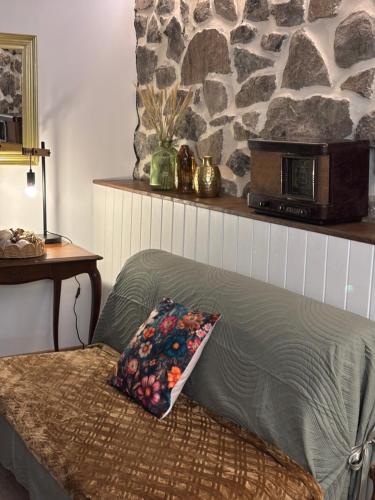 a bed with a pillow on it with a stone wall at Appartement Puy Mary By les Monts du Cantal in Murat