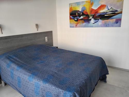 a bedroom with a bed and a painting on the wall at Villa vue sur la mer in Saintes-Maries-de-la-Mer