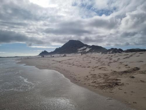 a beach with a mountain in the background with people on it at OceansCrest Seaview Apartment in Bettyʼs Bay