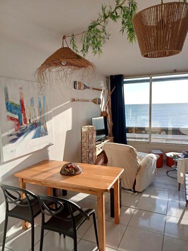 un salon avec une table et des chaises et l'océan dans l'établissement Le Paradis Bleu !, à Saint Cyprien Plage