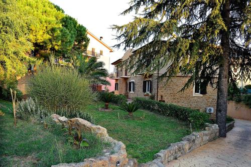 a house with a yard with trees and a stone wall at Il triclinio B&B in Piazza Armerina