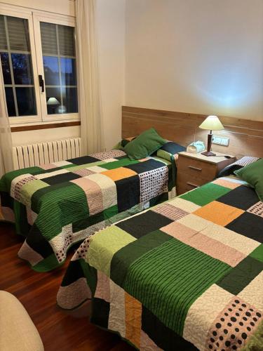 two beds in a room with green and colorful blankets at Casa Cancelas in Santiago de Compostela