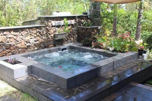 a hot tub in a garden with a stone wall at le mangue car hôte in Saint-Paul