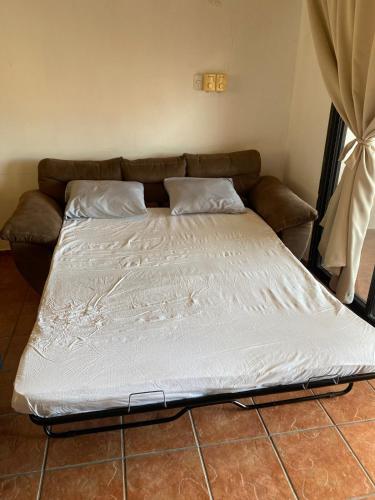 a large bed in a room with a couch at Apartamento equipado, con amplia piscina in Paquera