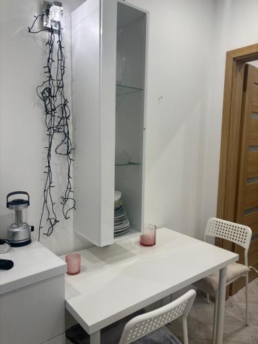 a white kitchen with a white table and chairs at Biały Dom in Świnoujście