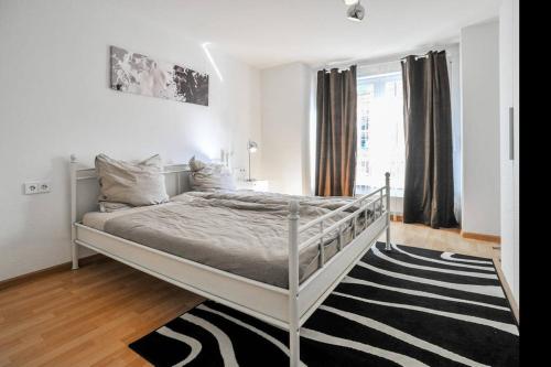 a white bed in a white bedroom with a rug at Traumwohnung Stuttgart in Stuttgart