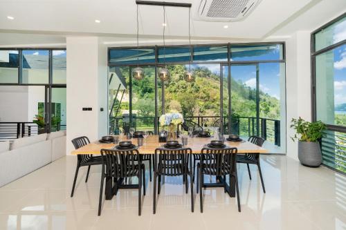a dining room with a table and chairs and large windows at Patong Cliff Villa Phuket 12 bedroom in Patong Beach