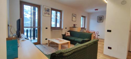 un salon avec un canapé vert et une table dans l'établissement Maison 4Emme, à La Thuile