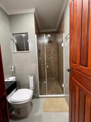 a bathroom with a toilet and a glass shower at Casa Amar Cabo Frio in Cabo Frio