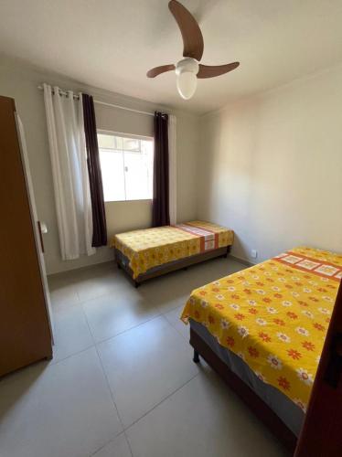a bedroom with two beds and a ceiling fan at Casa Amar Cabo Frio in Cabo Frio