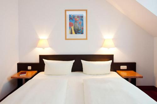 um quarto com uma grande cama branca e 2 candeeiros em A`ppart Hotel Garden Cottage em Dresden