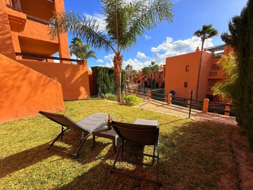 two chairs and a grill in the grass near a building at Piso de lujo Golf y Playa in Estepona
