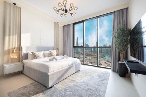 a bedroom with a bed and a large window at High-Floor Luxe 2BR Stunning Burj Khalifa & Fountain Views Direct Dubai Mall Access in Dubai