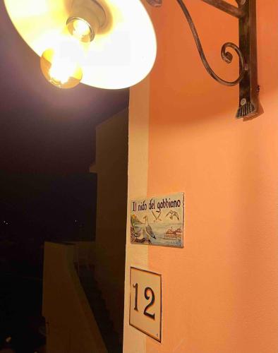 a light hanging on a wall with a sign on it at Il Nido del Gabbiano in Procida
