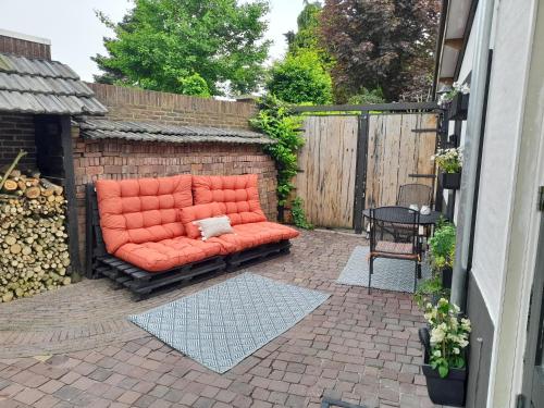 an orange couch sitting on a brick patio at De Vier Jaargetijden in Gassel