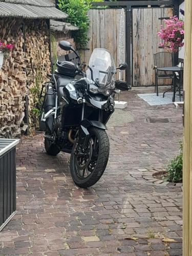 a black motorcycle parked on a brick patio at De Vier Jaargetijden in Gassel