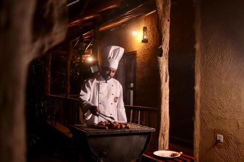 a chef standing in a kitchen preparing food on a grill at Villa Springwater Dellawa in Ihalapanangala