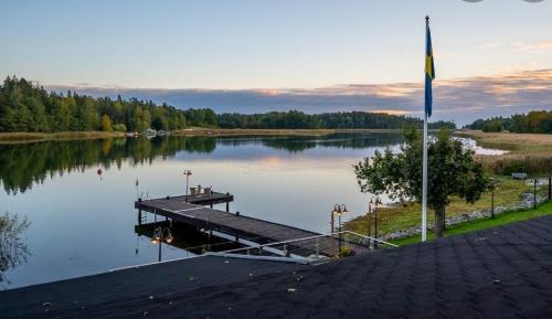 a dock on a body of water with a flag at Villa Solsa in Nynäshamn