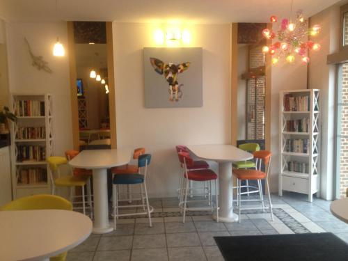 a restaurant with tables and chairs in a room at Hotel Couleurs Sud Centre-ville Gare Charleville-Mézières in Charleville-Mézières