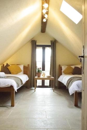 une chambre mansardée avec deux lits et une fenêtre dans l'établissement Gite de la foret, à Saint-Plantaire