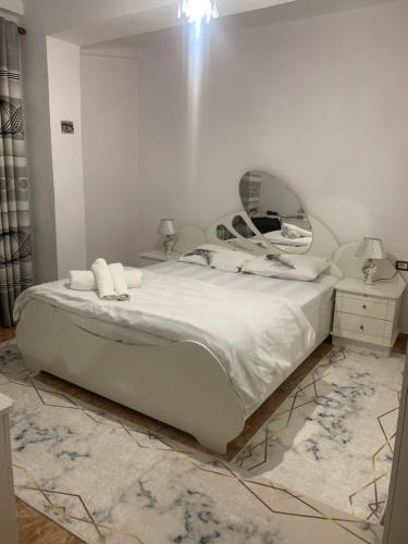 a bedroom with a large white bed and a mirror at Fabio's Apartament in Pogradec
