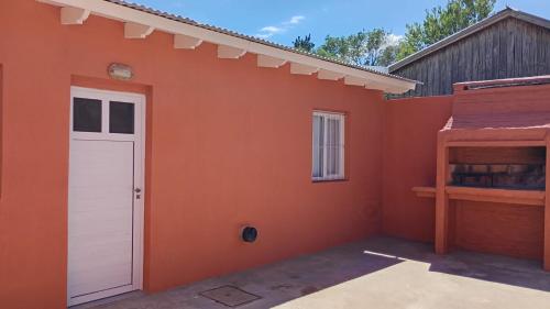 ein kleines orangefarbenes Haus mit einer weißen Tür in der Unterkunft Dpto en San Antonio Oeste 2 pax in San Antonio Oeste