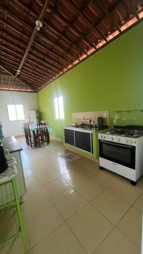 a kitchen with a stove and a green wall at Casa Verde Japaratinga in Japaratinga