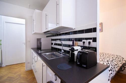 une cuisine avec un comptoir avec un évier et un micro-ondes dans l'établissement Stylish Escape in the Vibrant 11th arrondissement, à Paris