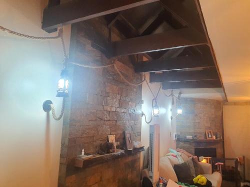 a living room with a stone fireplace with lights at heated pool, barbecue area and full house in Licán Ray