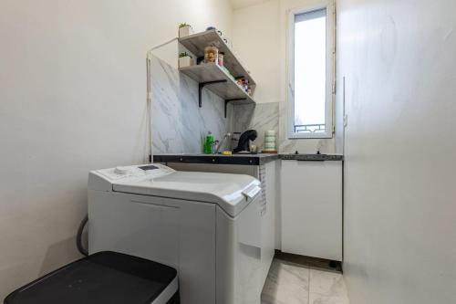 a small white kitchen with a sink and a washer at Grand T1 confortable - Calme et Proche de Paris in Montreuil