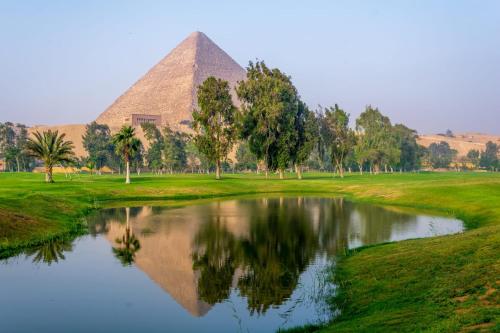 a pyramid and a pond in front of a pyramid at Moonlight golf view in Cairo