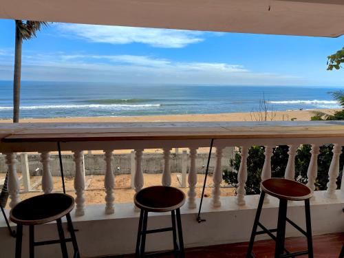 a balcony with two stools and a view of the beach at Le Serene Independent Beach Villa in Kottakupam