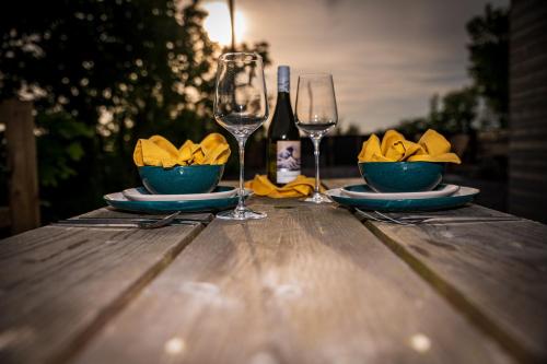 a table with two wine glasses and a bowl of napkin at Lowern, Luxury Lodge with Hot Tub and Games Room in Menai Bridge