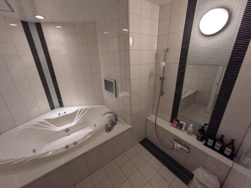 a white bathroom with a tub and a mirror at ホテル リズコート HOTEL Liz court in Sendai