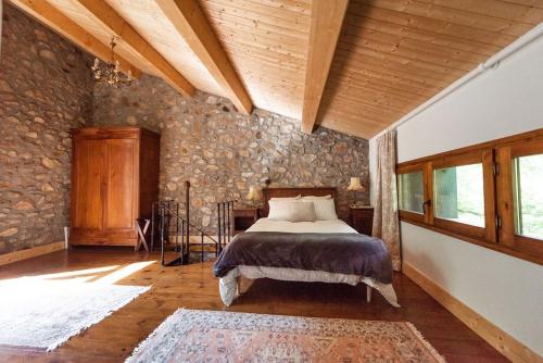 une chambre avec un lit et un mur en pierre dans l'établissement Luxury mountain cottage with pool access - La Bergerie, à Corsavy