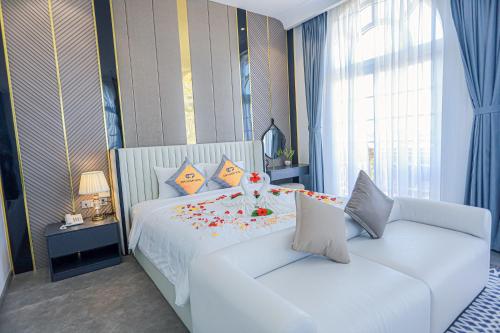 a bedroom with a white bed and a couch at Premium CGP Hotel Hoi An in Hoi An