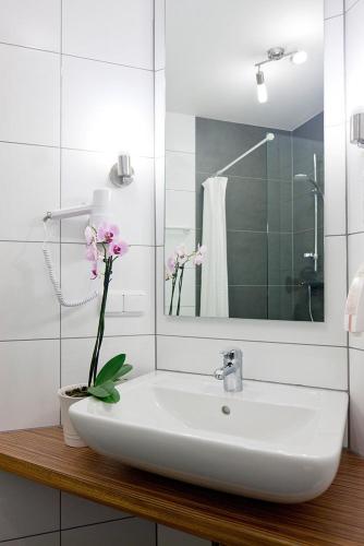 a bathroom sink with a vase with flowers on it at Hotel Garden Cottage mit kostenfreien Parkplätzen in Dresden