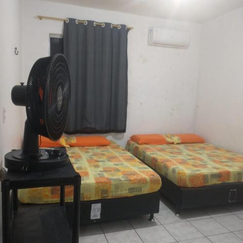 a room with two beds and a fan on a table at Casarão Farol da Marise Sol in Belém
