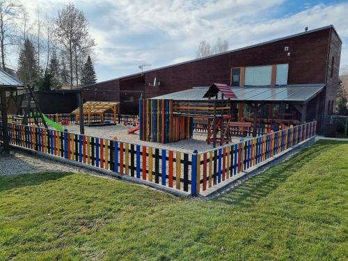 a fence in front of a building with a playground at Apartmán v Bečva Resortu in Horní Bečva