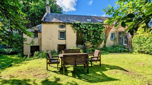 a table and chairs in front of a house at Historic 1600 Cottage with Hot Tub, Private Estate in Stirling