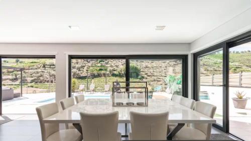 a dining room with a white table and white chairs at Valadouro Amazing Villa in Douro Valley - Pool in Espinhosa