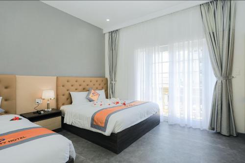 a hotel room with two beds and a window at Premium CGP Hotel Hoi An in Hoi An