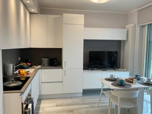 Una cocina con gabinetes blancos y una mesa con sillas. en Il Gioiello Del Borgo, en Borghetto Santo Spirito