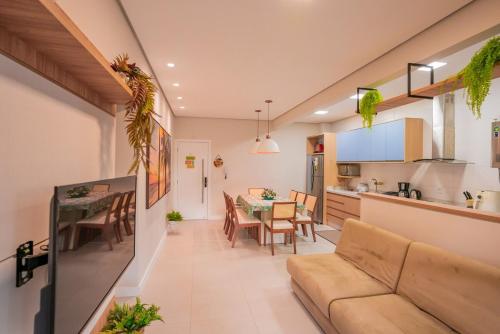 a living room and kitchen with a couch and a table at Apartamento Exclusivo a 600m da Praia de Palmas Piscina Banheira de Imersão aquecida rede in Governador Celso Ramos