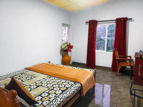 a bedroom with a bed and a window with red curtains at La Belle Homestay in Kandy