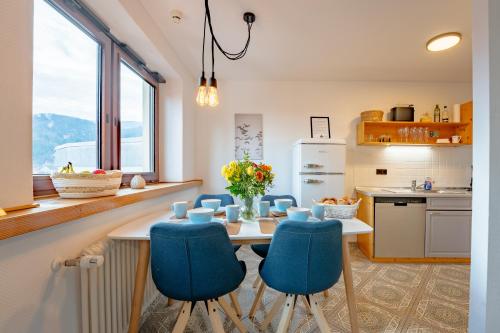a kitchen with a table and blue chairs at SCHLOSSBERG RESIDENCES - Design-Apartments im Herzen der Pfalz in Sankt Martin
