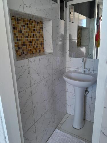 un bagno bianco con lavandino e specchio di Casa Marisol Maresias a São Sebastião