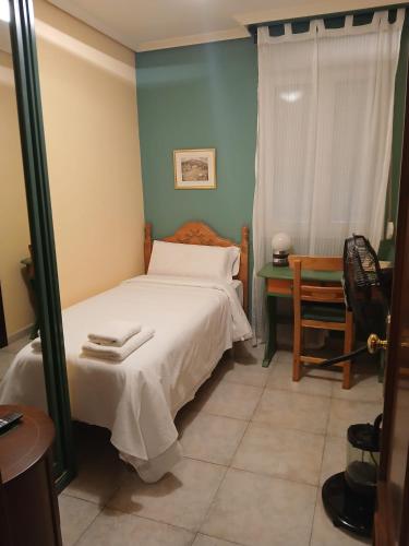 a bedroom with a bed and a table and a window at Hotel Mataleñas in Santander