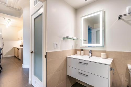 a white bathroom with a sink and a mirror at DTLA 2BR Rooftop Jacuzzi & Sunset Views in Los Angeles